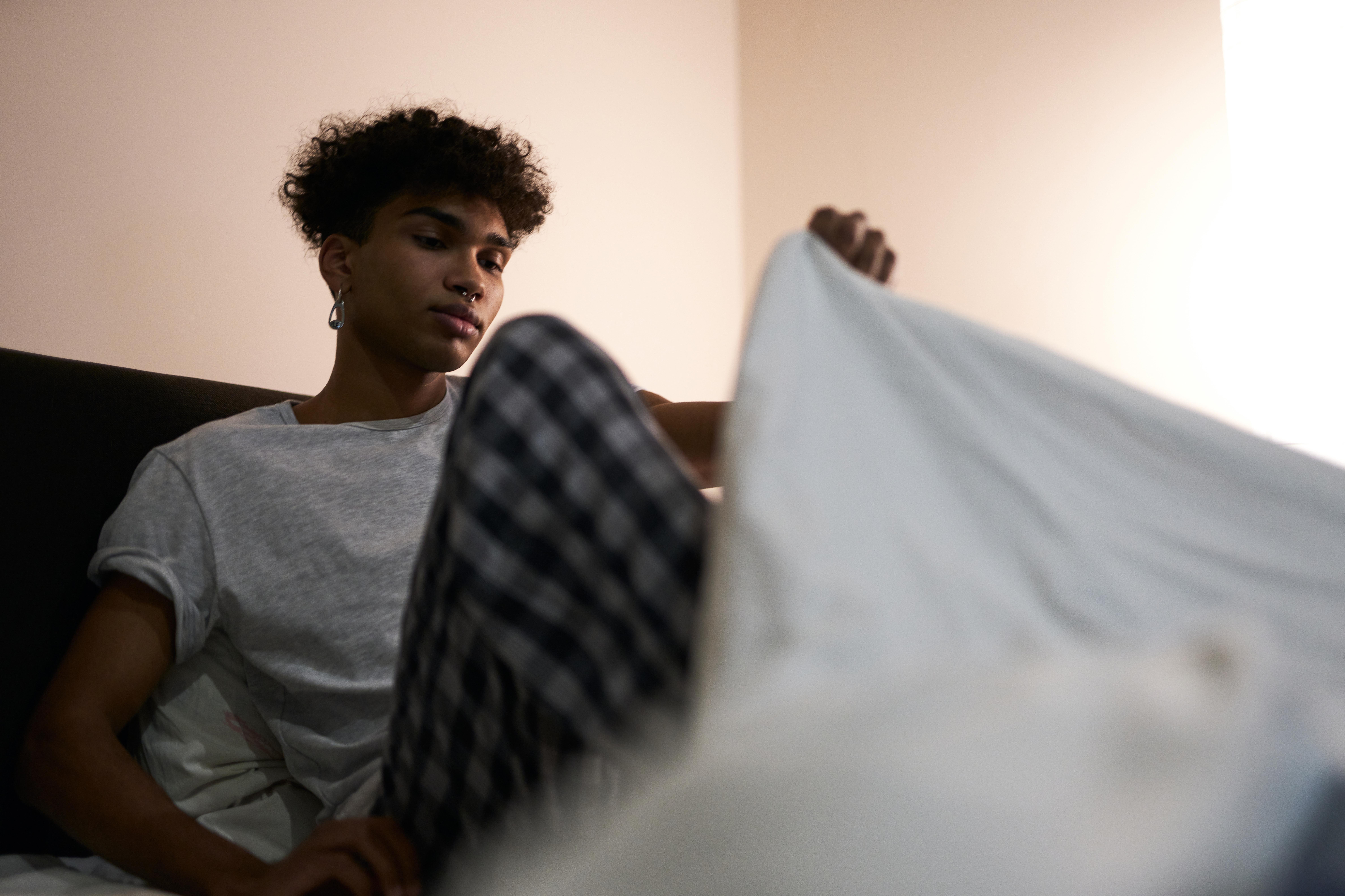 young man getting into bed to sleep