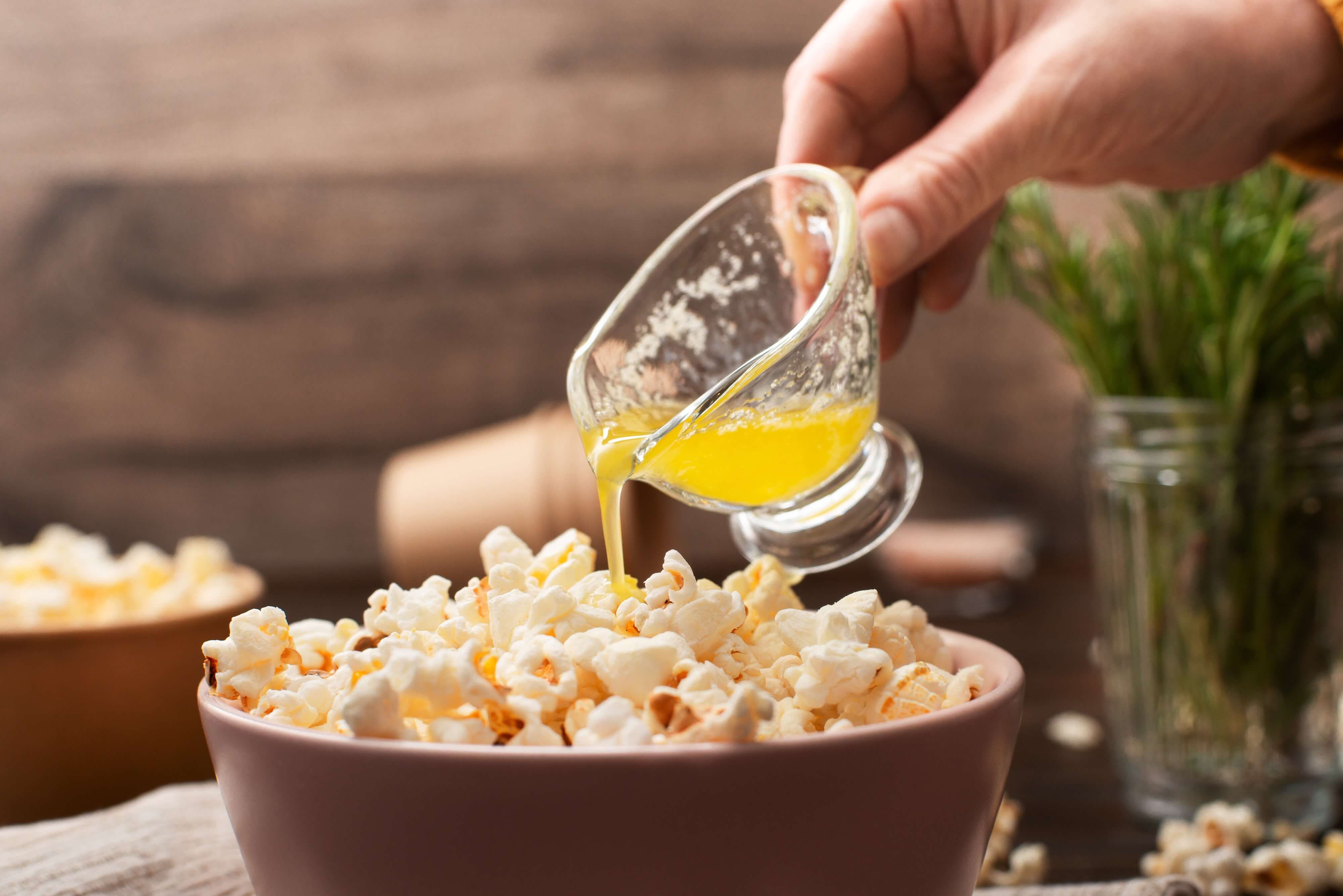 pouring melted butter over popcorn