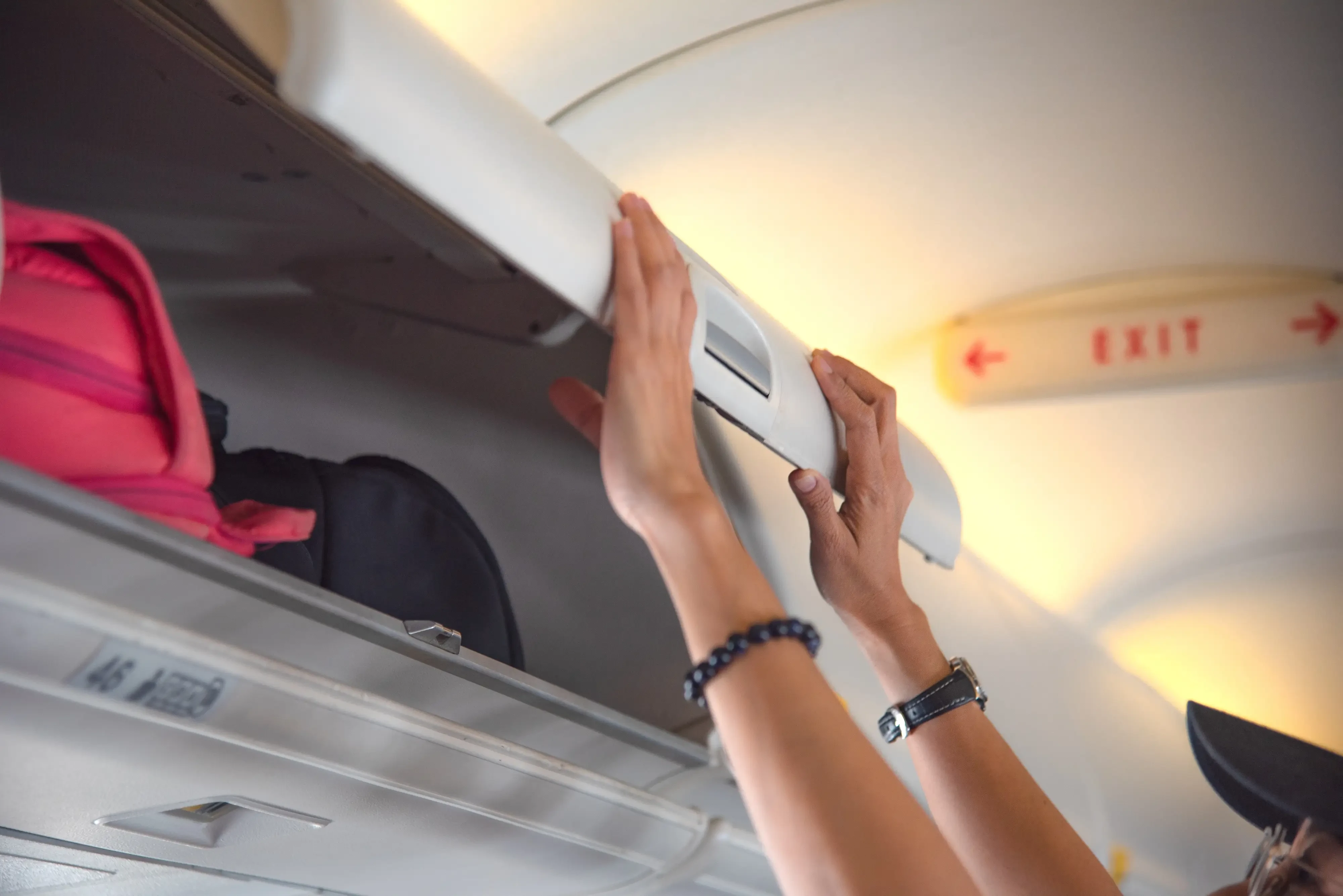 woman closing carry on compartment in a plane