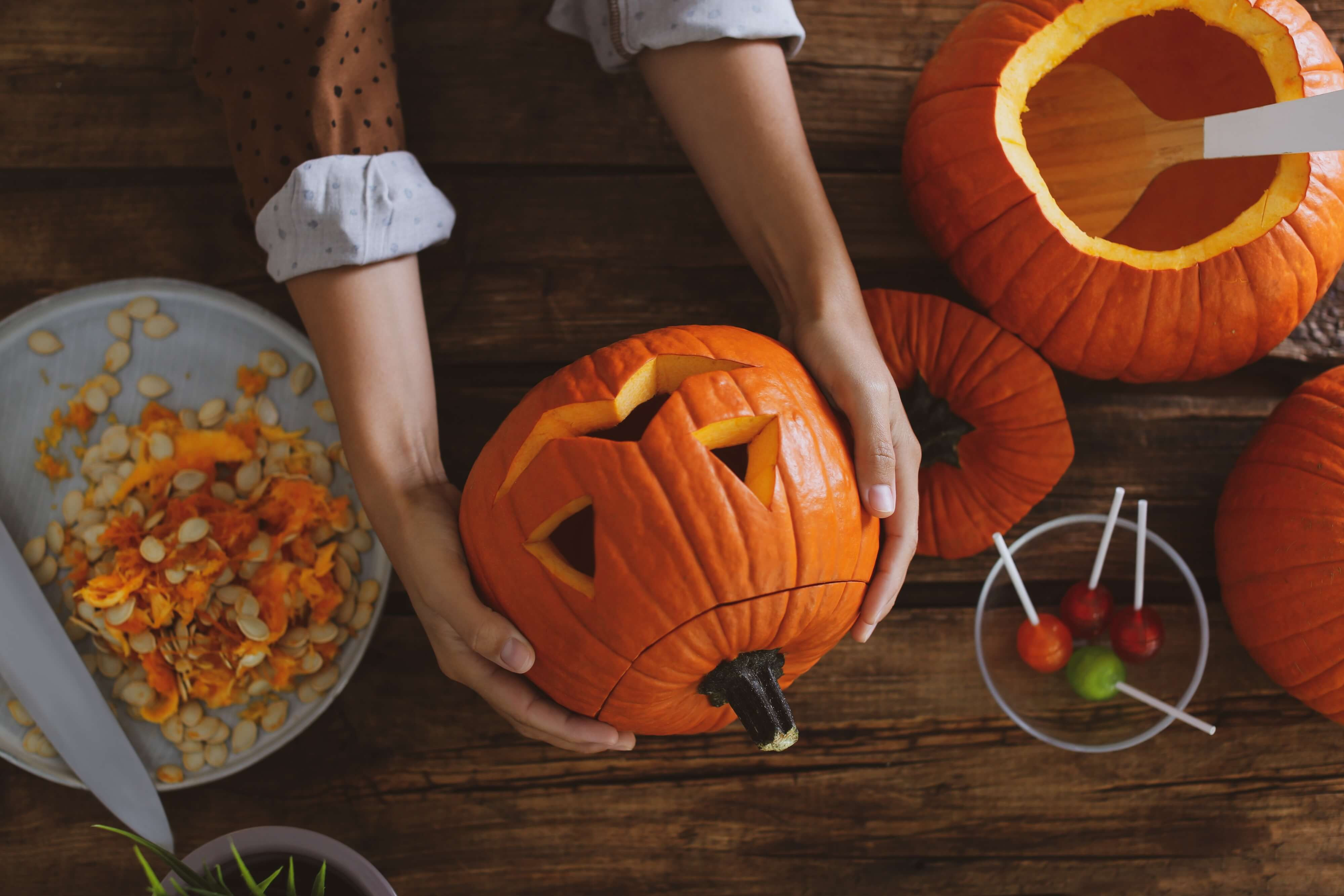 hands carving out a jack o lantern