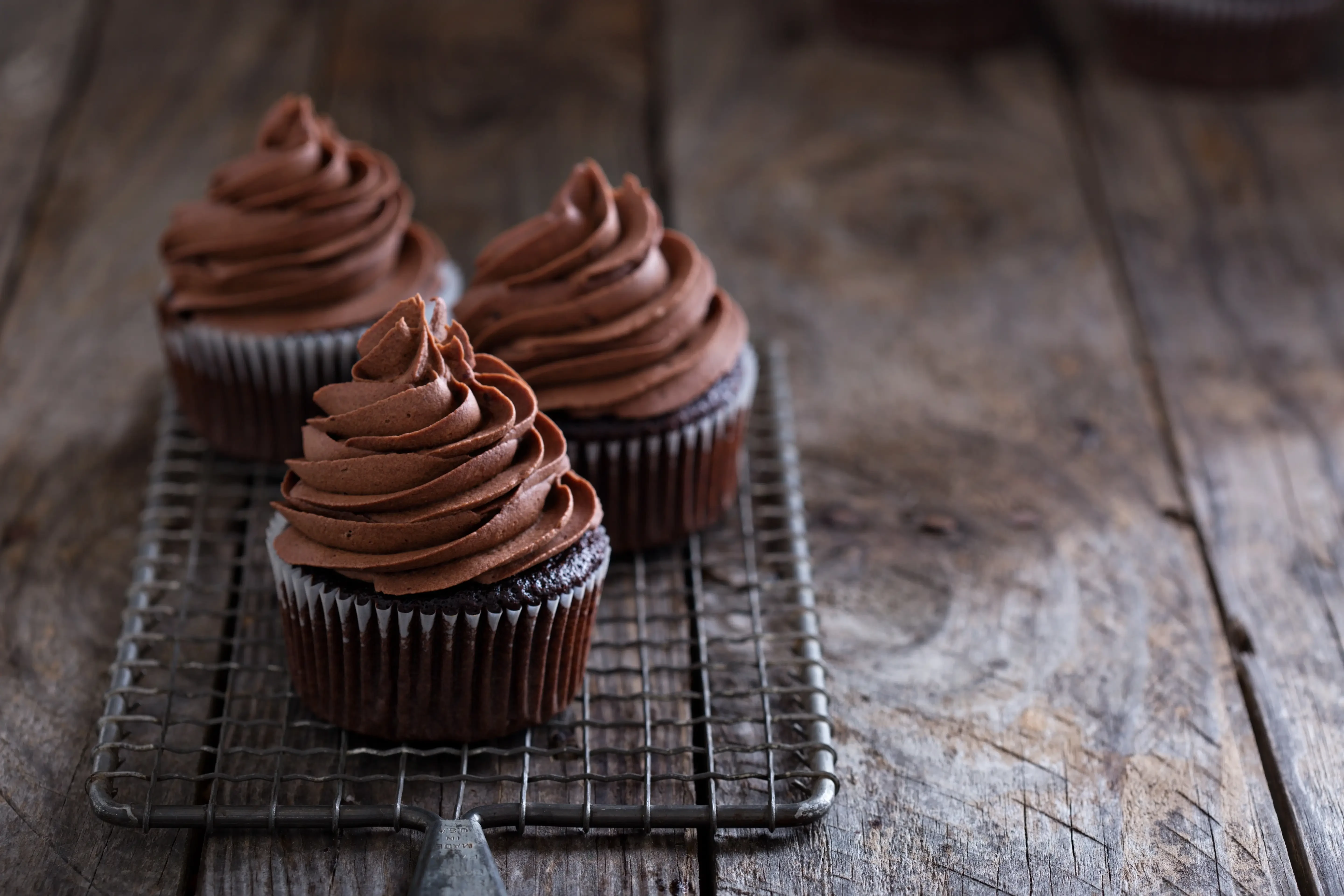 cannabis chocolate cupcakes on a wooden table with a wired net to cool