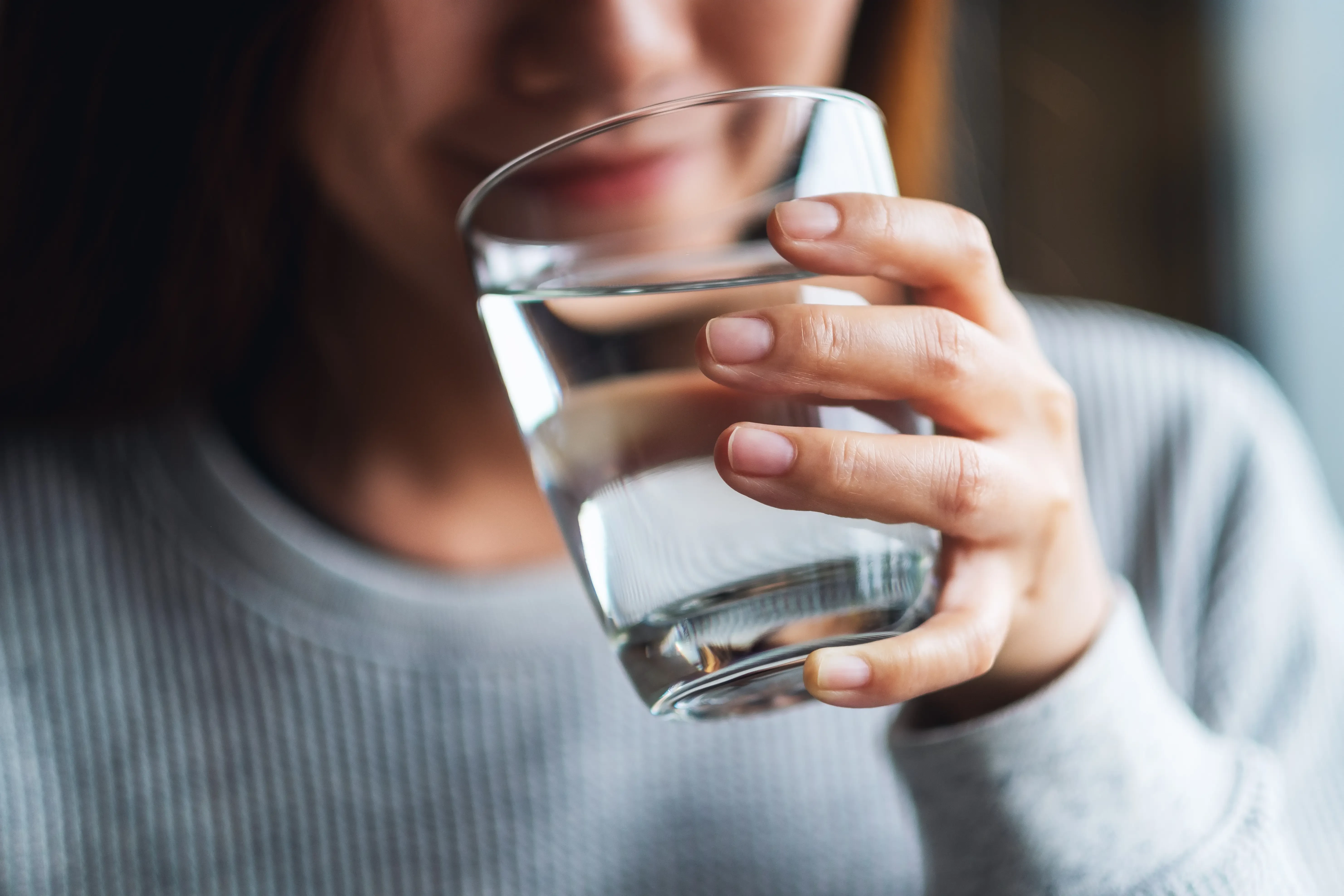 woman taking a drink of water from a glass