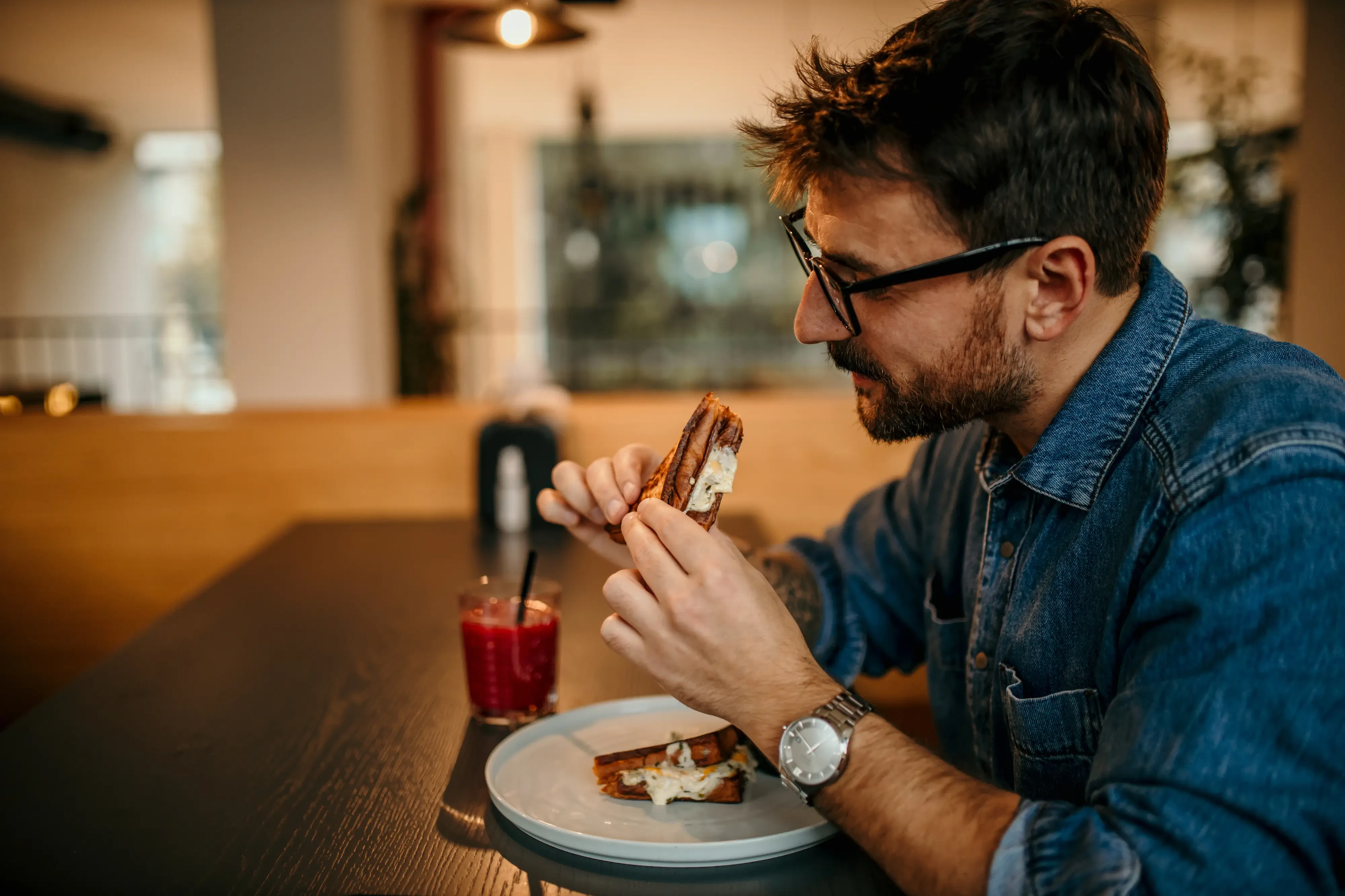 man enjoying a delicious sandwich and drink