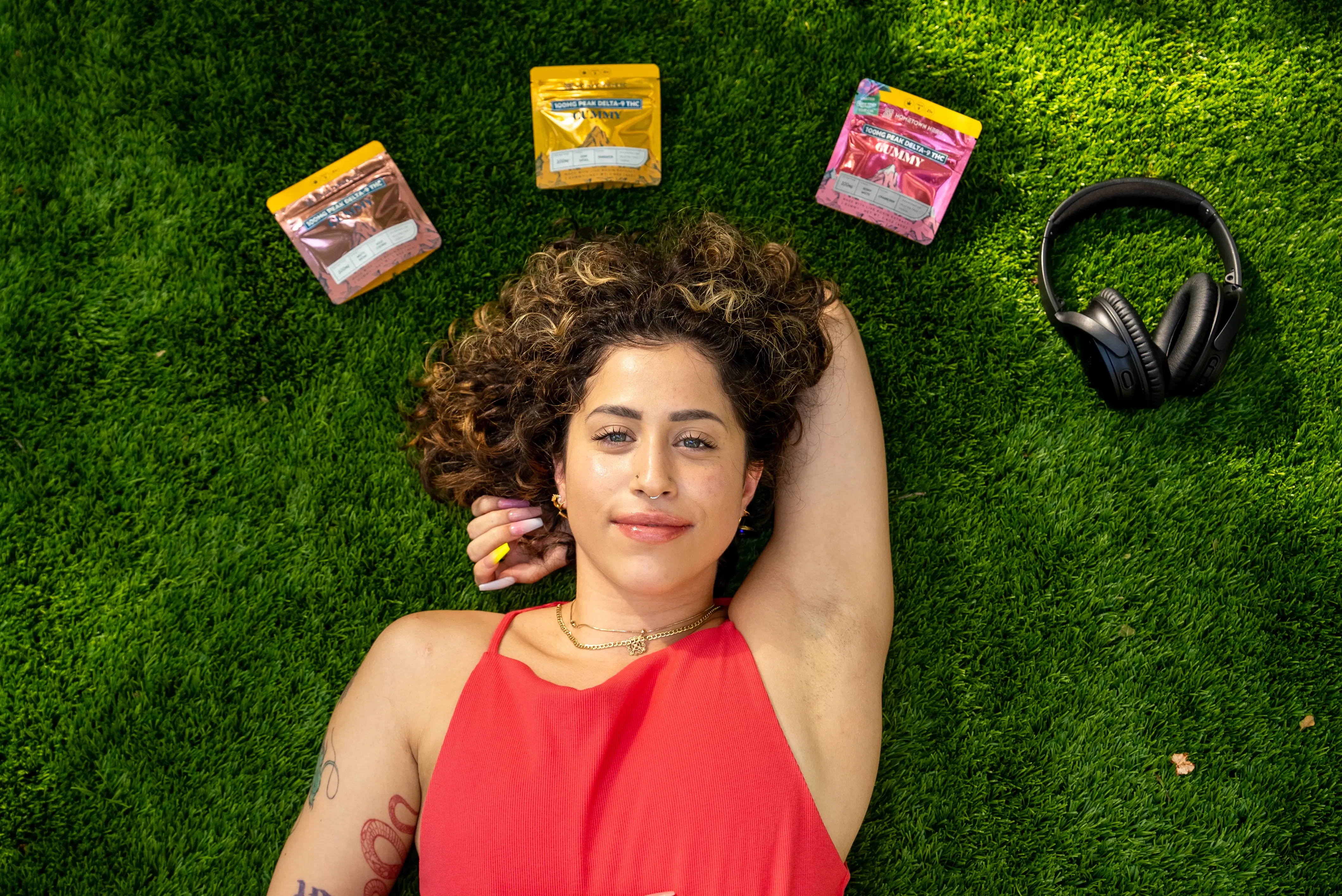 woman smiling brightly with edibles around her on the grass