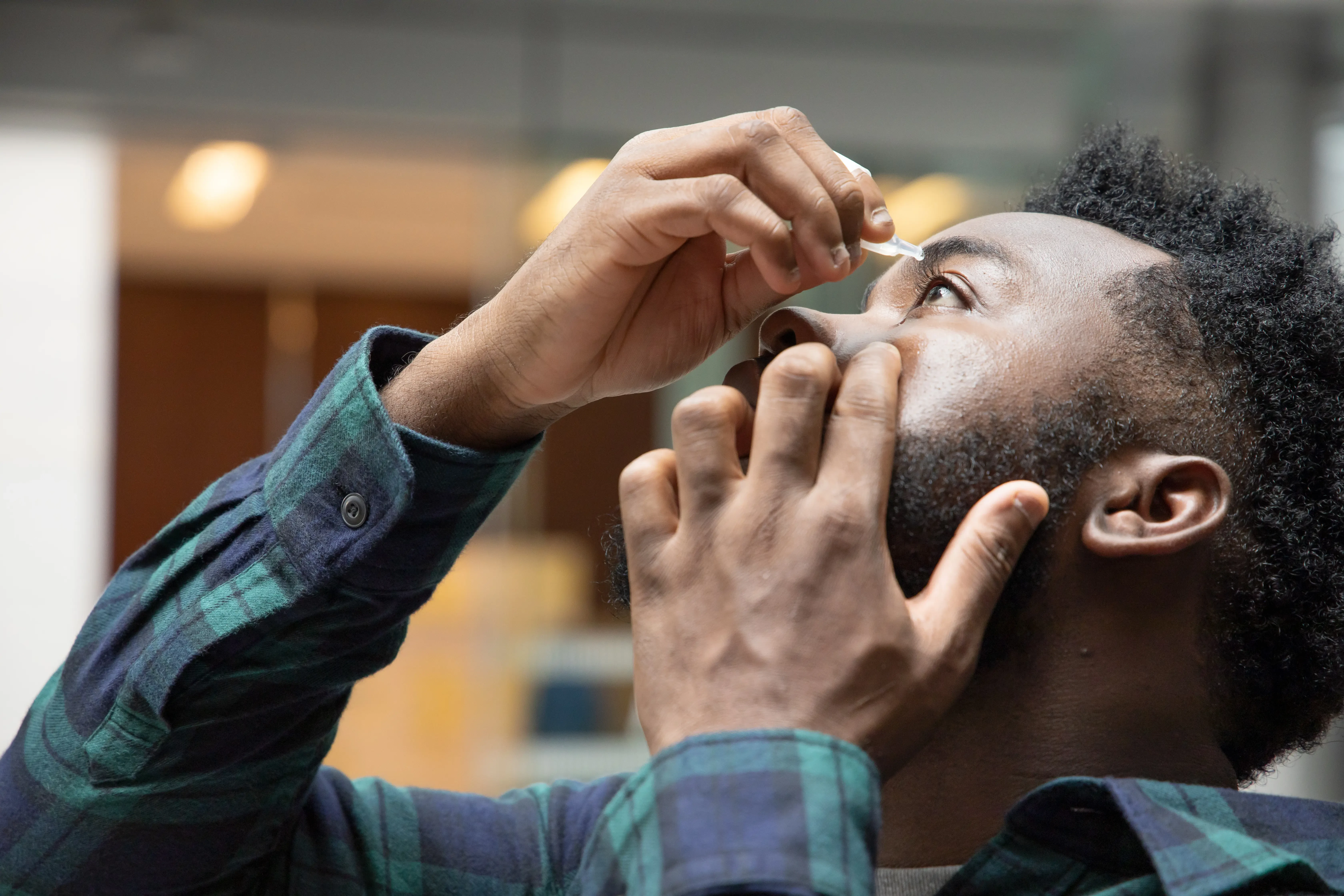 man applying eye drops
