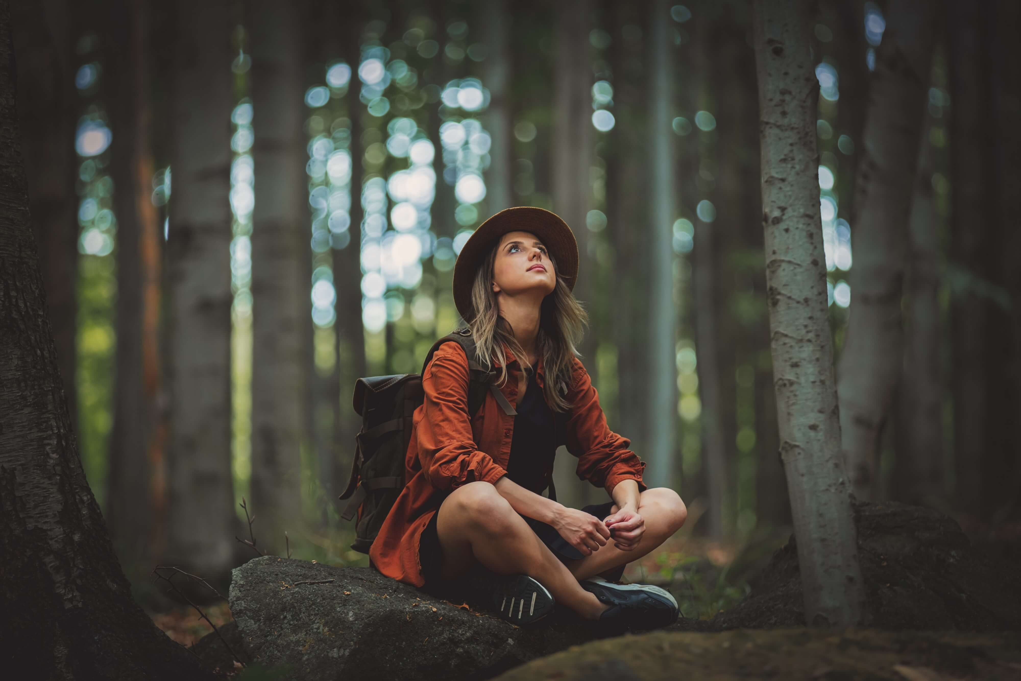 woman in a brimmed hat reflecting on life in the woods