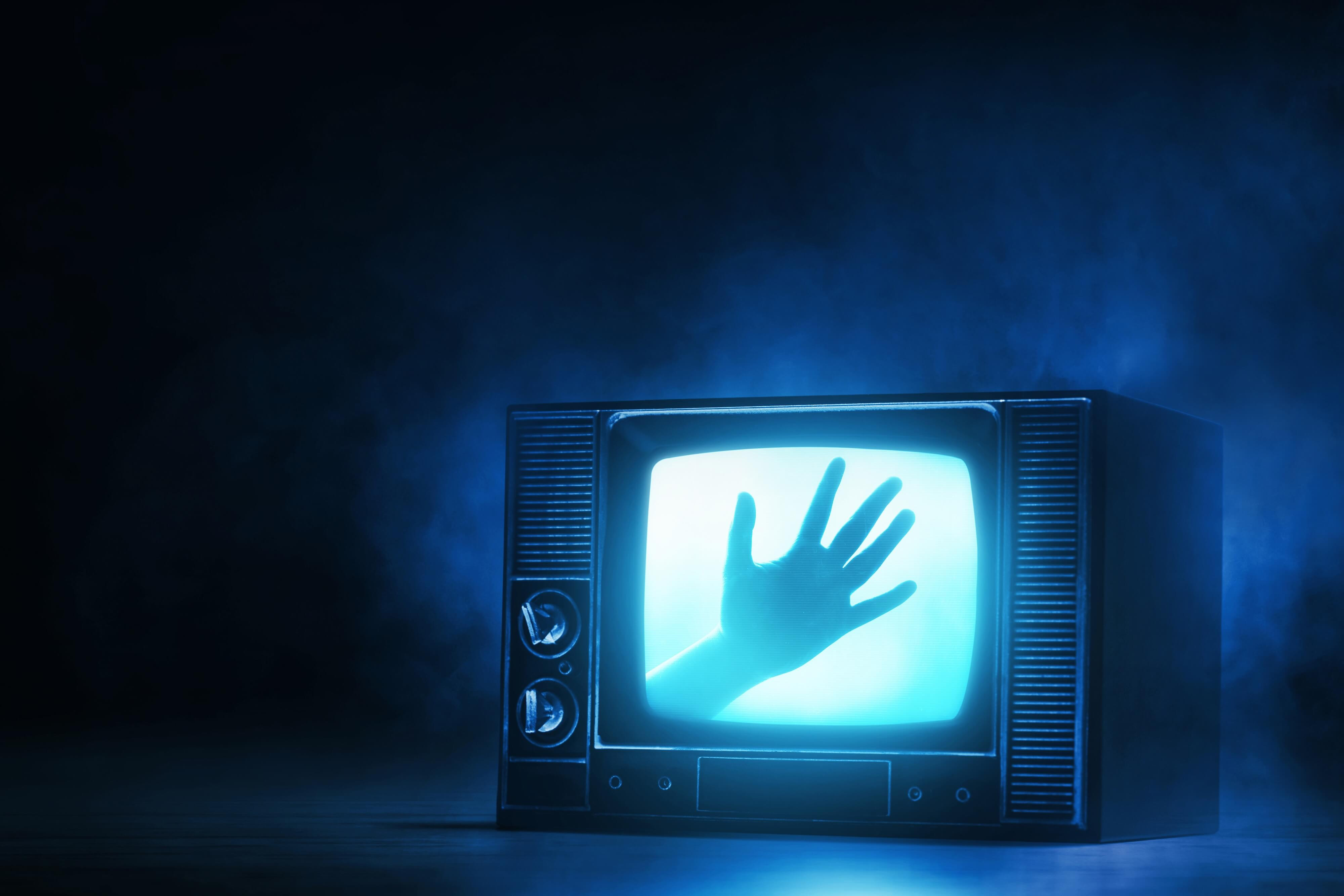 eerie hand on TV screen symbolic of horror movie