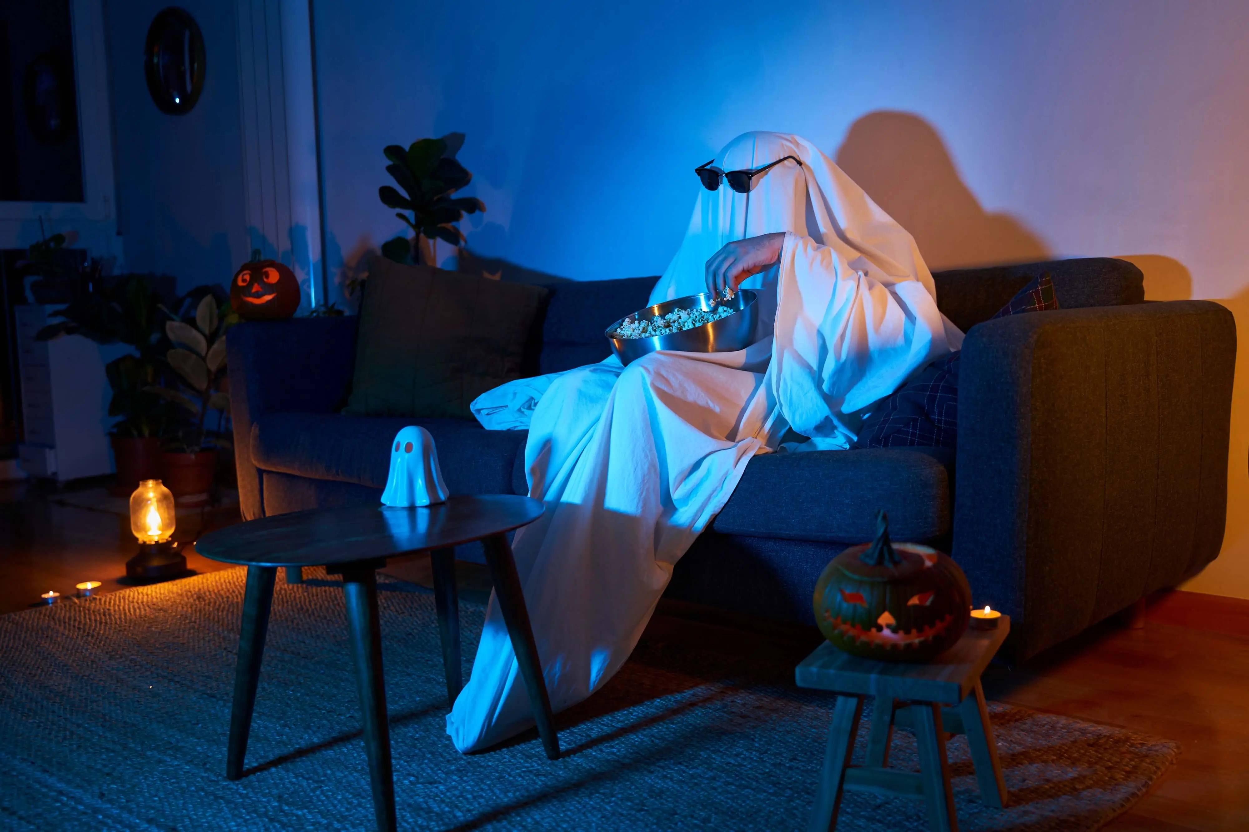 man dressed up as a ghost watching horror movies in his living room