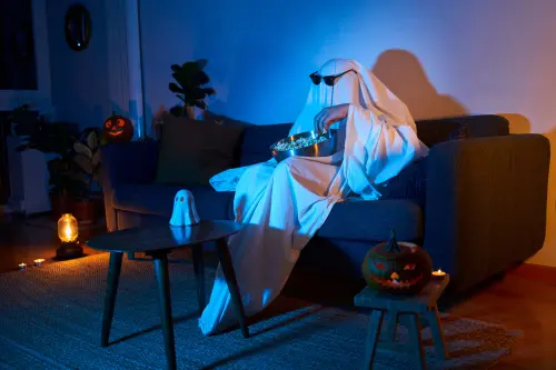 man dressed up as a ghost watching horror movies in his living room