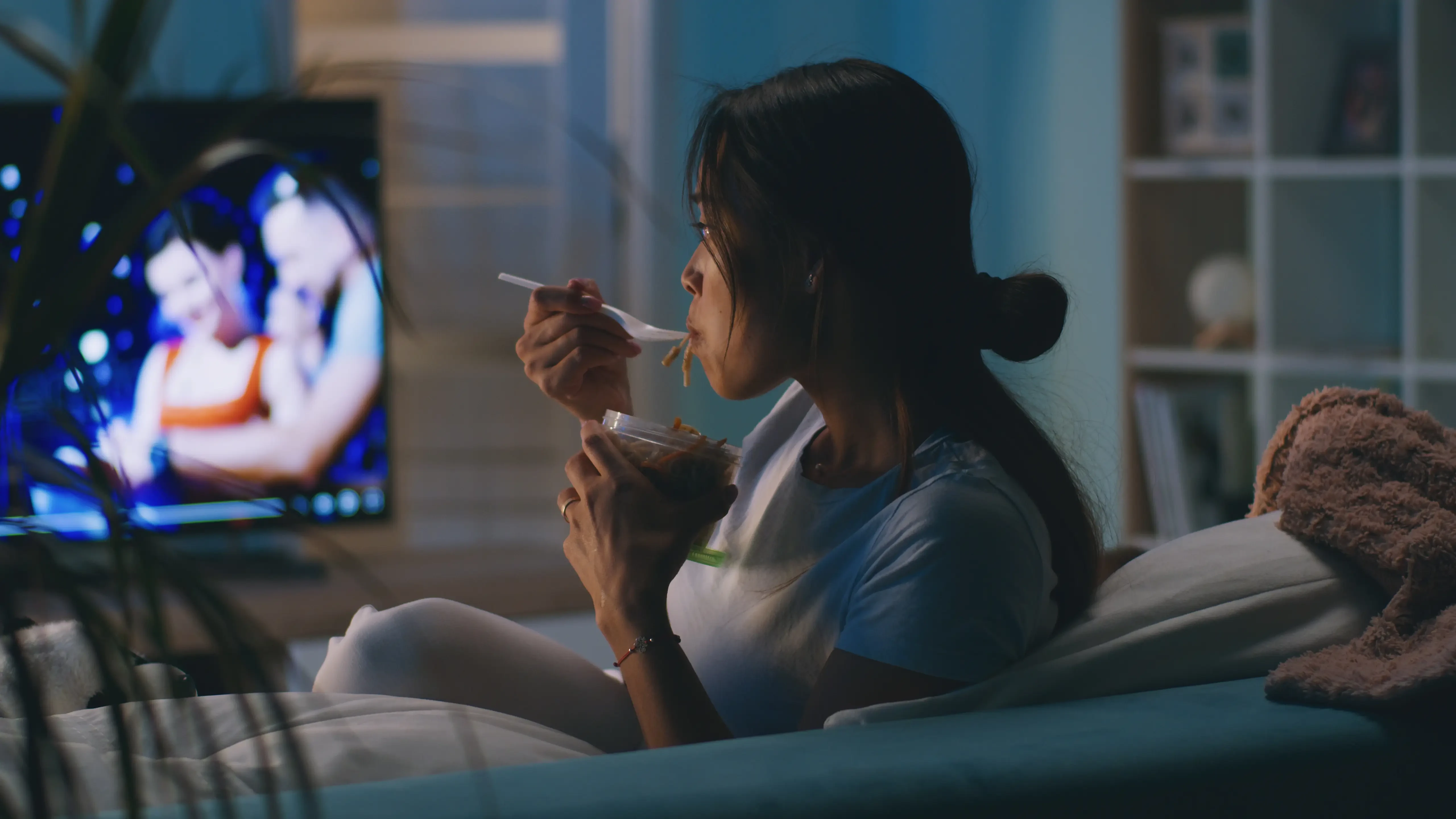 woman slurpling leftover spaghetti at night