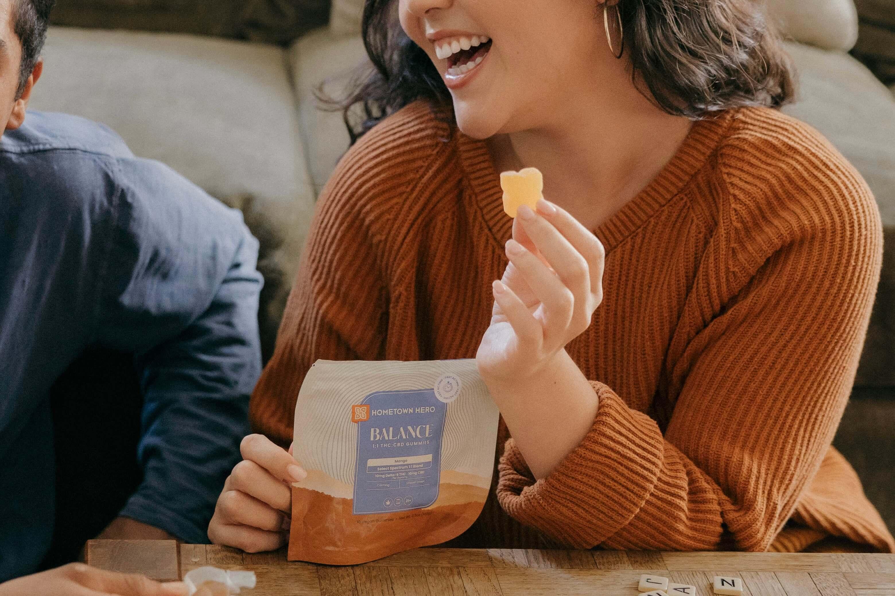 woman holding a gummy in her hands laughing