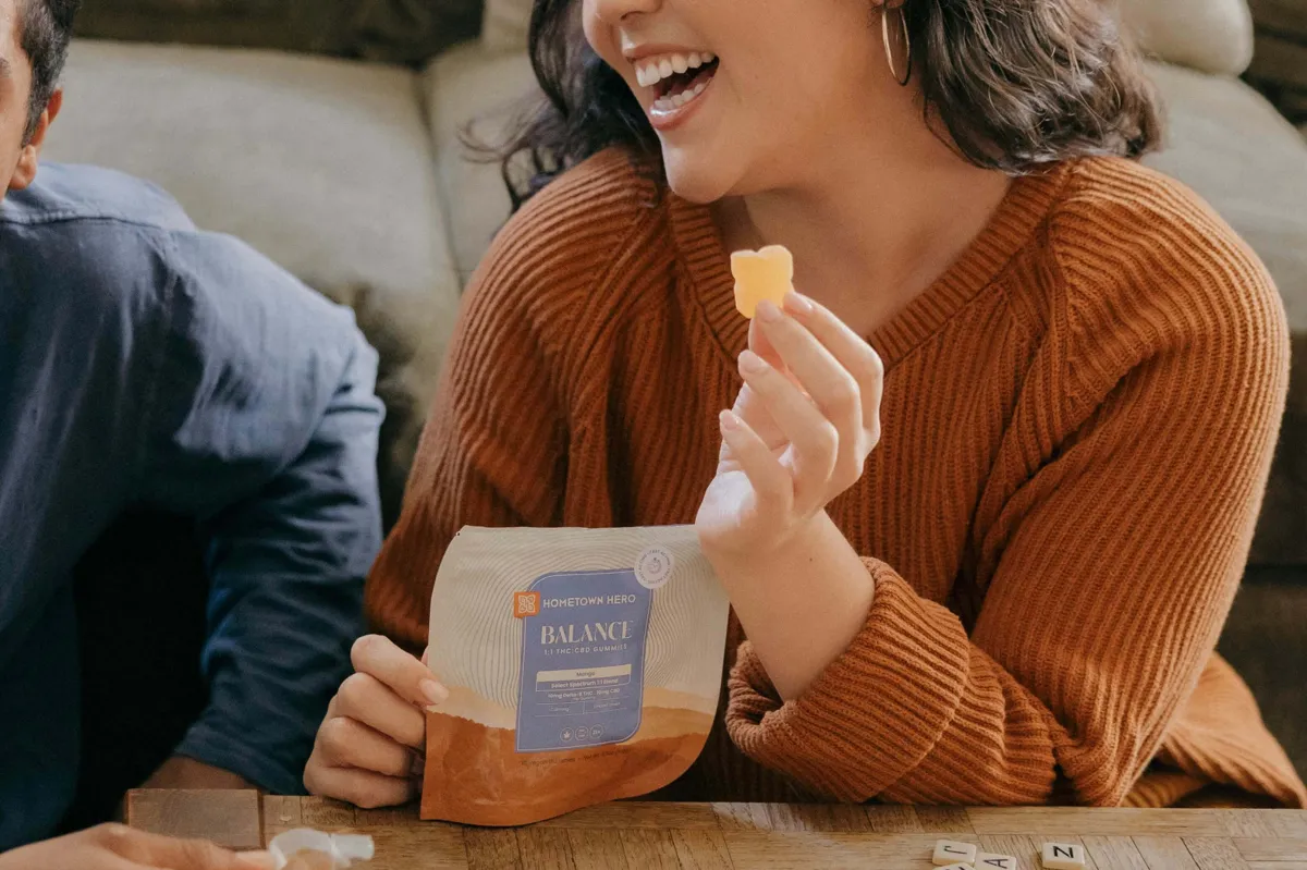 woman holding a gummy in her hands laughing