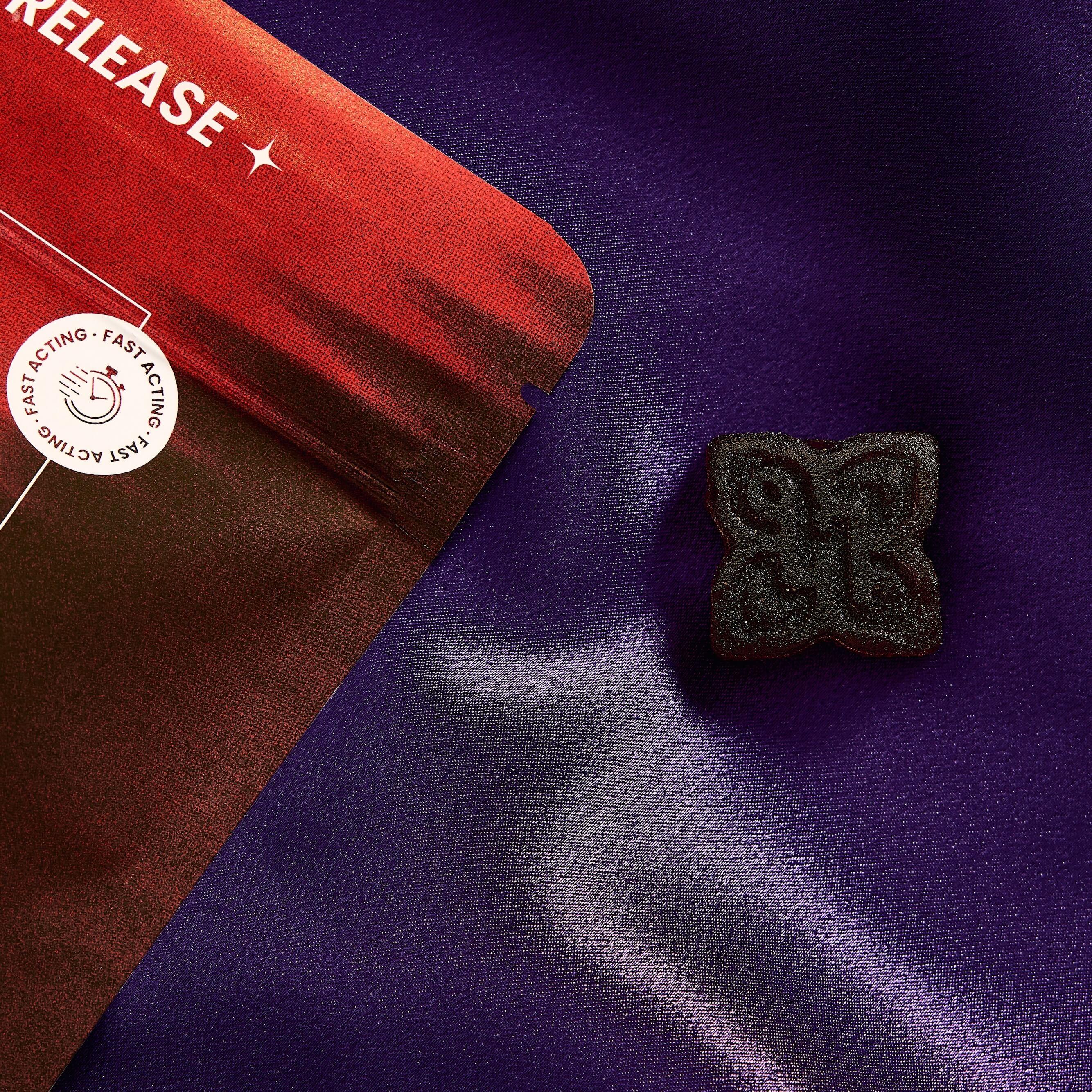 dark hued arousal gummy for men next to a red bag