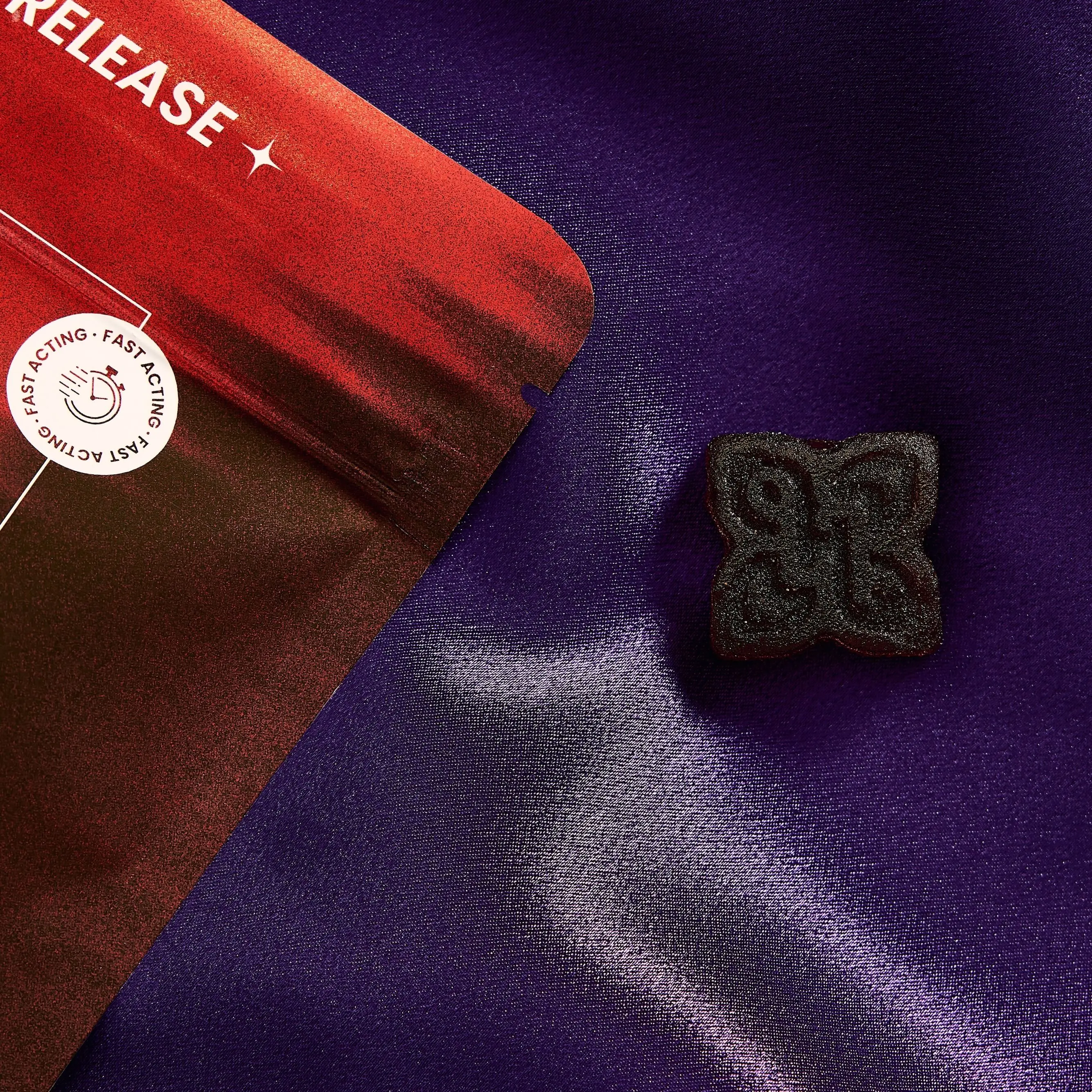 dark hued arousal gummy for men next to a red bag
