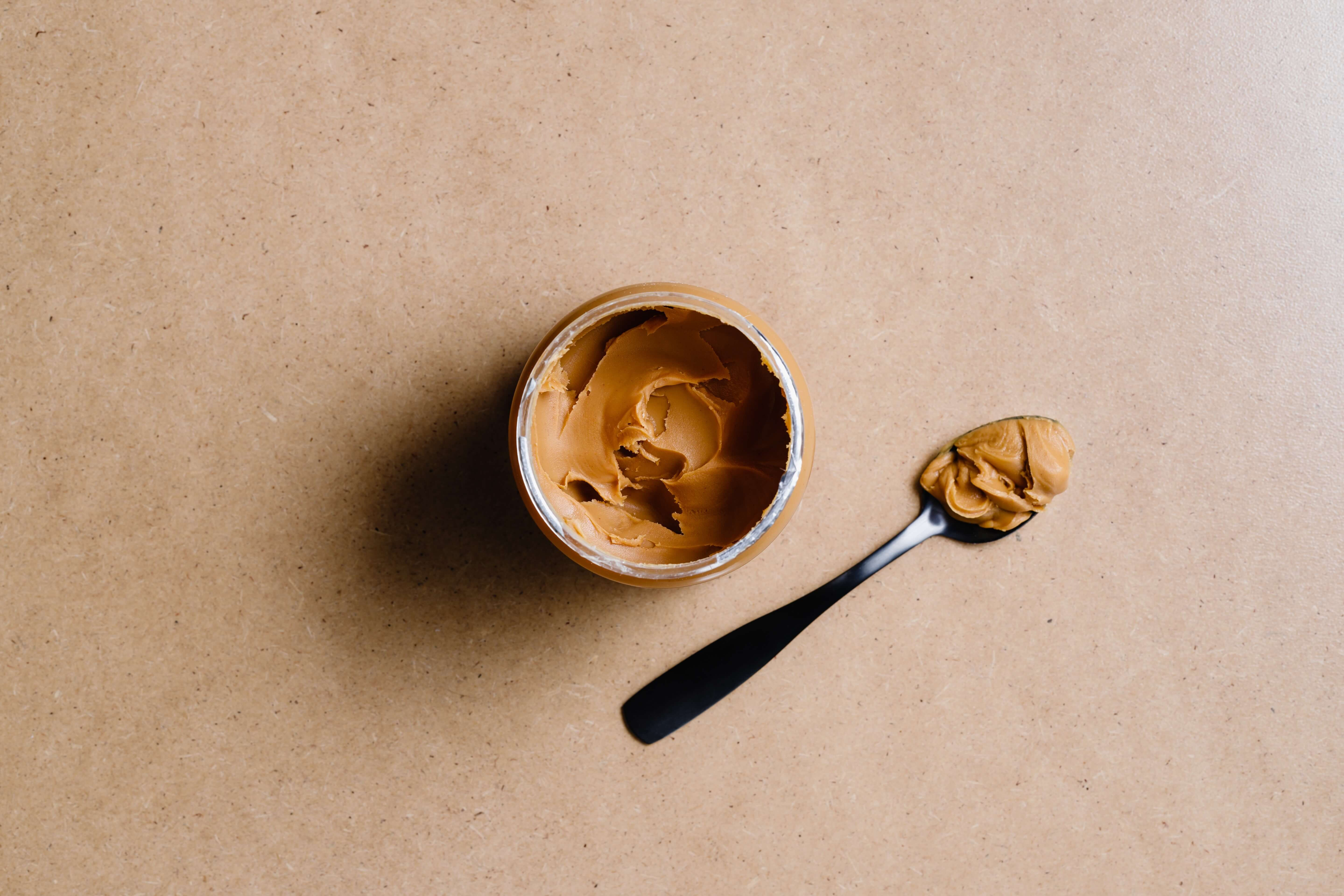 Spoon of peanut butter next to jar