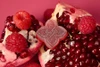 closeup of a red gummy on pomegranate and raspberry