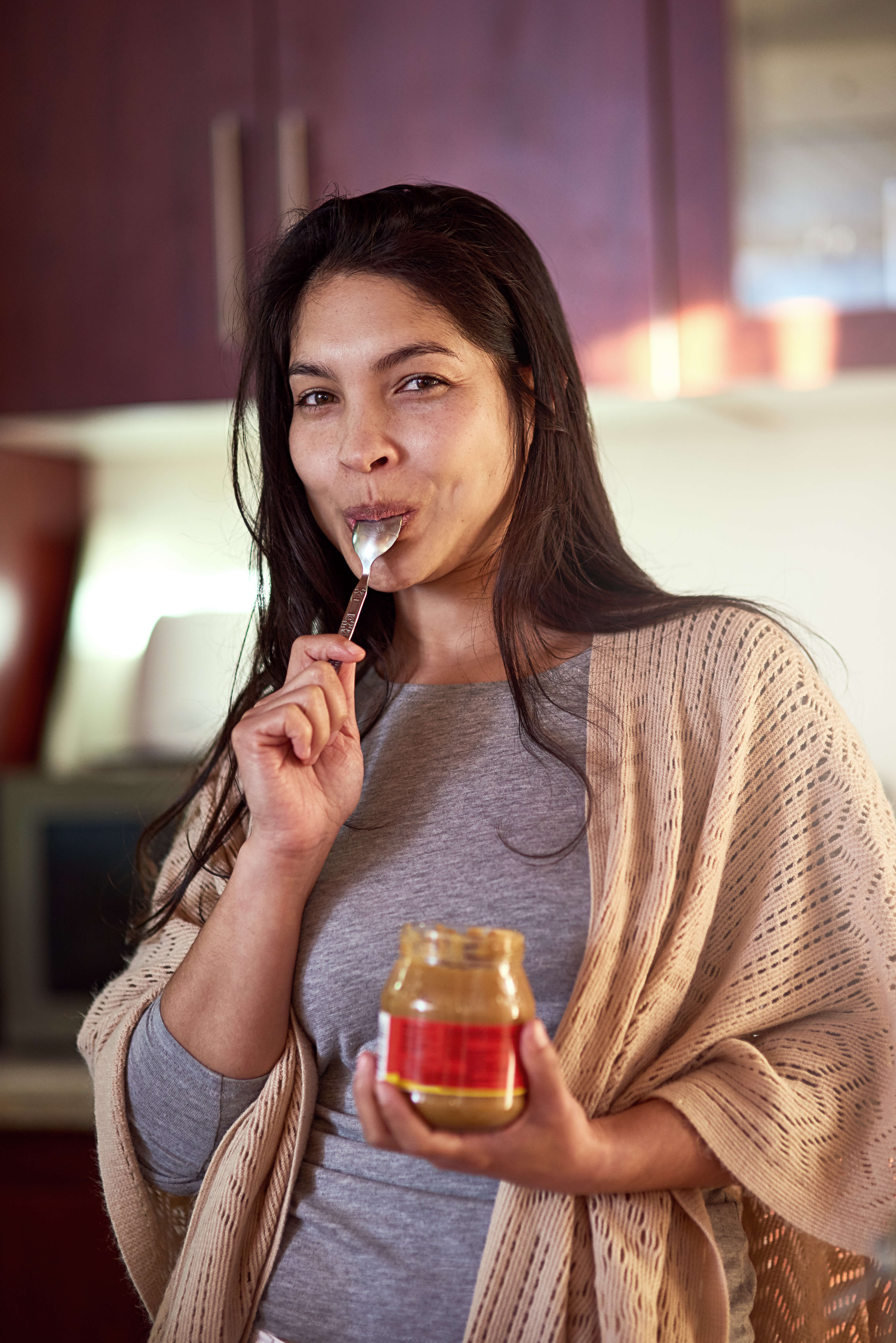 woman consuming peanut butter with a smile