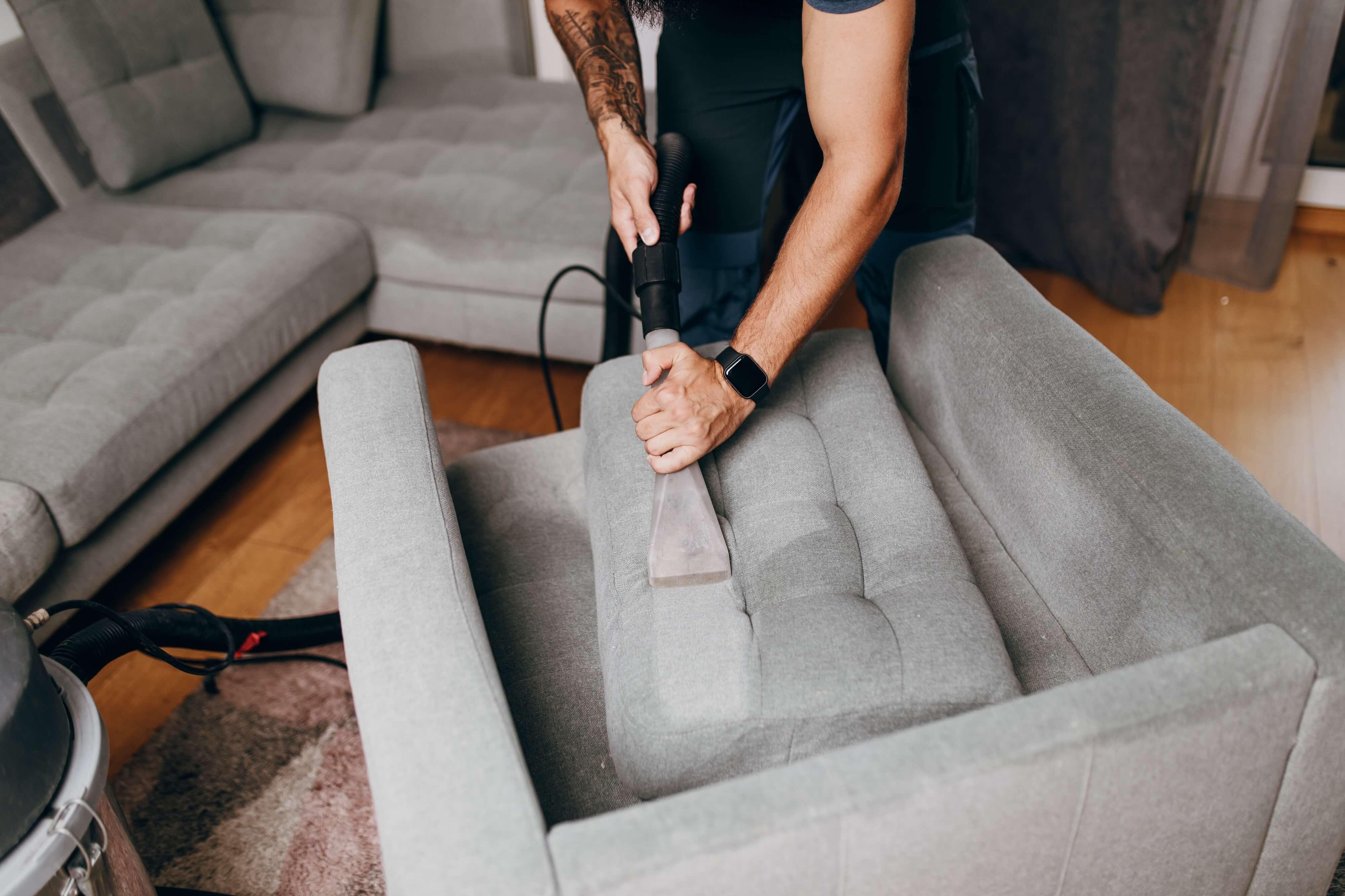 man steam cleaning the upholstery on his couch