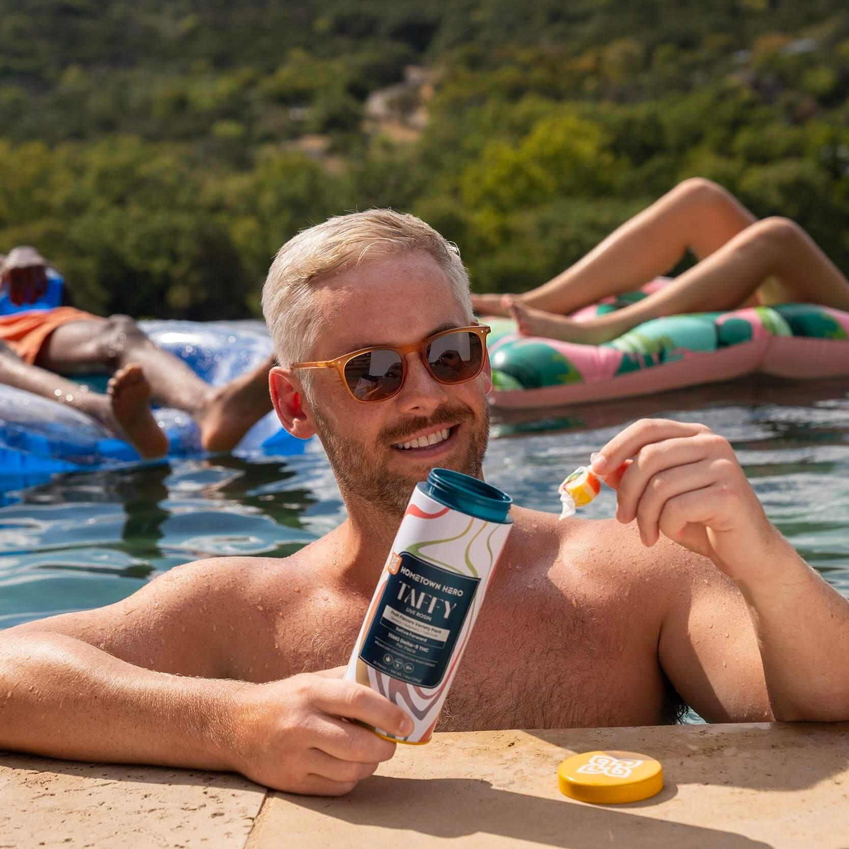 man taking taffy out of tin beside the pool