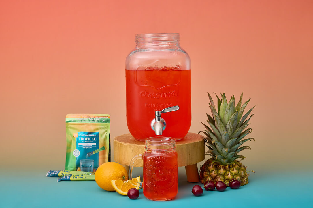 tropical thc drink mix on a table with glass of water to mix it into