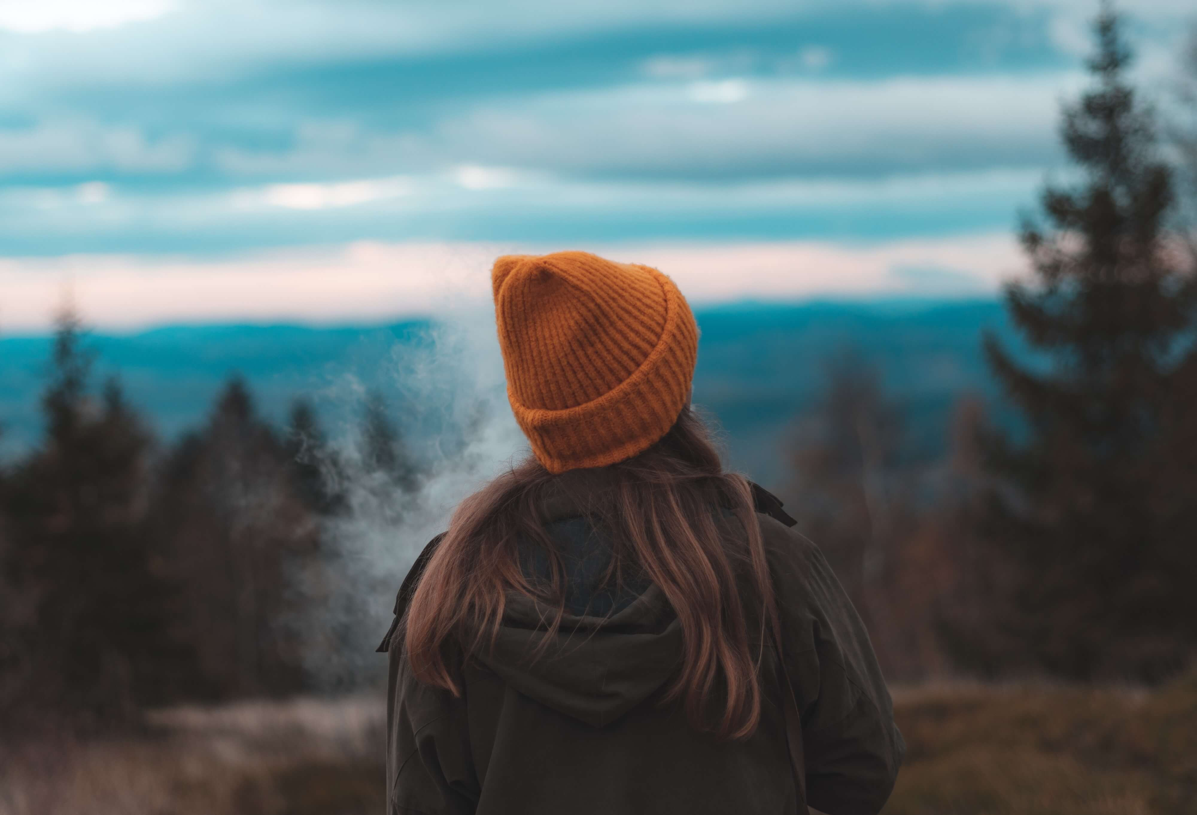 exhaling woman vaping in the woods