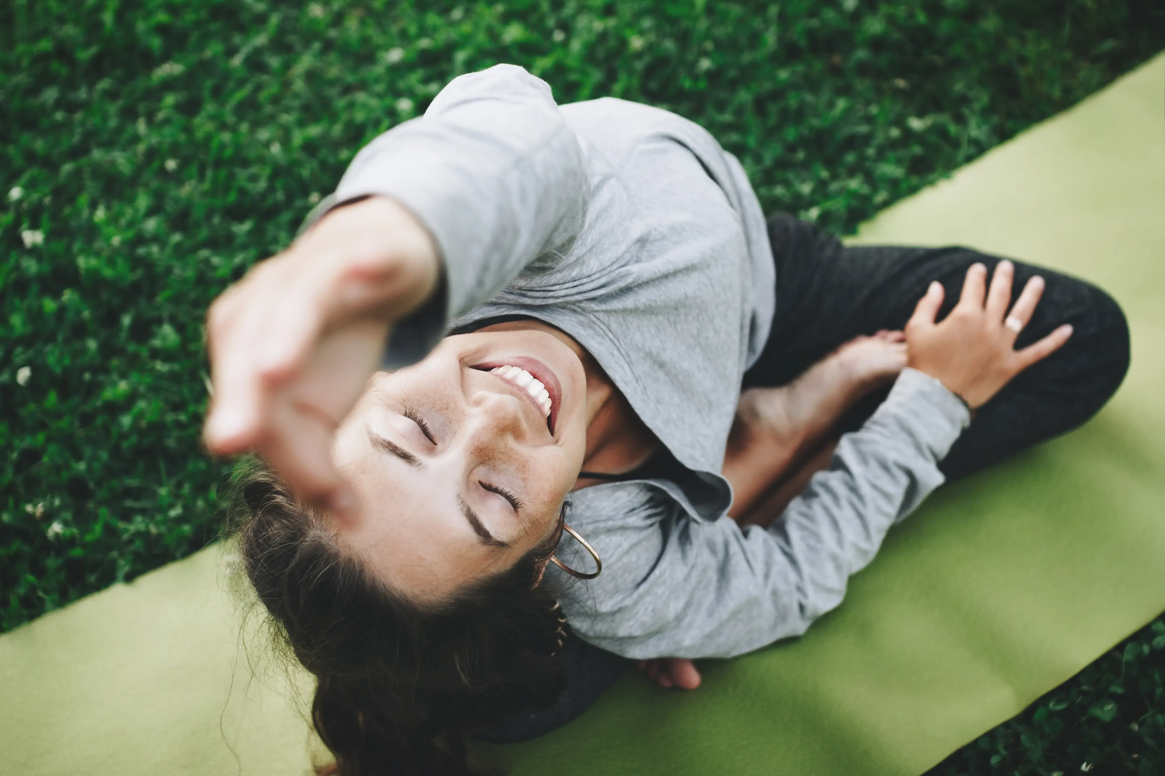 woman smiling while doing yoga in the park
